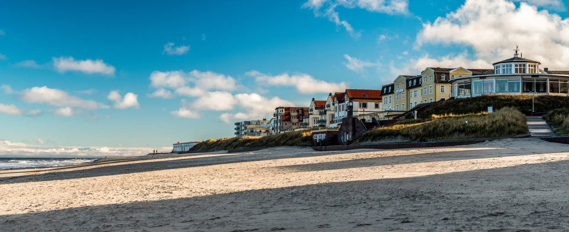 Reihenhauszeile am Strand mit Blick auf das Meer und den blauen Himmel mit Wolken.